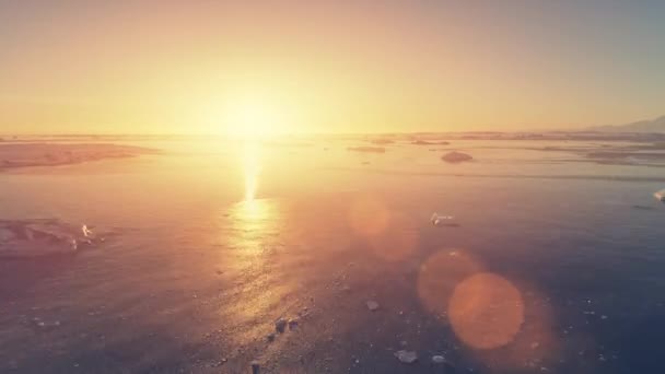 南極のオレンジの日没 日焼け止め エピック空中ドローン飛行 海の水と氷河の氷の上を高速撮影しました 明るいビームを与えられた黄色い太陽ライト — ストック動画