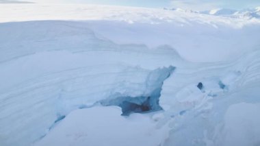 Antarktika Yarımadası 'ndaki beyaz buzuldaki mavi buz mağarası. Havadan yakın çekim. Antarktika panoramik dron uçuş görüntüsü. Kutup buzullarının arasında kar. Donmuş suyun etrafındaki buzdağında bir mağara. Donmuş toprak. Antarktika