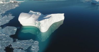 Buzdağı güneşli bir günde buz gibi Antarktika okyanusunu sürüklüyor. Eriyen buzullar sakin mavi sulara yansıyor. Küresel ısınma İklim değişikliği. Sinematik ekoloji sahnesi. Kutuplardaki donmuş vahşi hava aracı panoraması