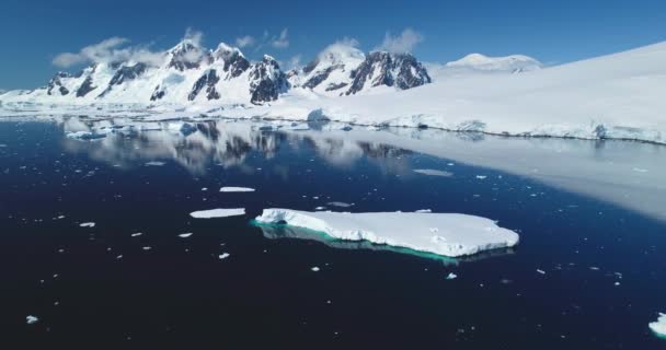 南极洲的雪覆盖了高山的冬季风景 冰川漂浮在极地冰封的海洋里 蔚蓝的天空在阳光灿烂的日子里 全球变暖和气候变化 北极探险 空中无人驾驶飞机全景 — 图库视频影像