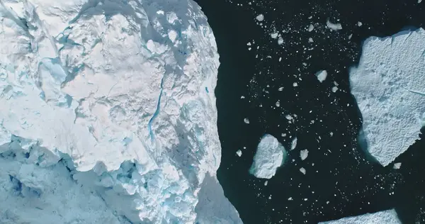 Top down icebergs at ocean bay aerial. Environment climate change, global warming. Melting glacier in ice fjord in Antarctica. Arctic nobody nature landscape in Unesco World Heritage Site drone shot