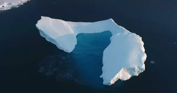 Melting Arctic iceberg aerial view. Glacier float in ocean water. Climate change and global warming problem. Polar nature environment. Wildlife North Pole winter landscape. Drone flight panorama