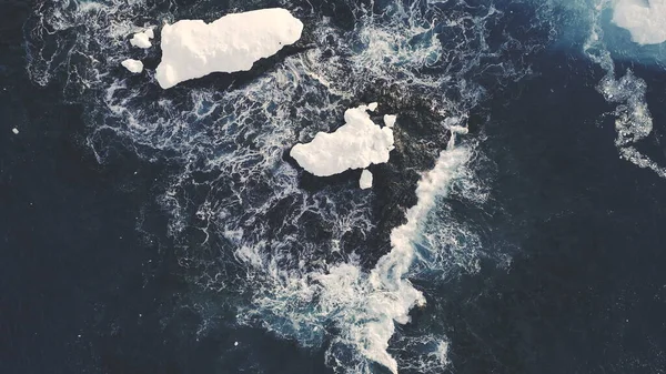 Icebergs Among Antarctica Ocean. Top Down Aerial Flight Over Ice Cold Polar Water. Zooming Out Shot Of Snow Covered Glaciers Surrounded By Raging Waves. Antarctic Winter Landscape. 4k Footage.