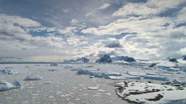 Hava uçuş bitti Antarktika okyanus. Zaman atlamalı. Hiper sukut. Bulutlar gökyüzü üzerinde hareket hızlı. Buzdağları bakış robot, güneşli bir okyanusta yüzen adet buz. Yüce dağlar arka plan kar kaplı