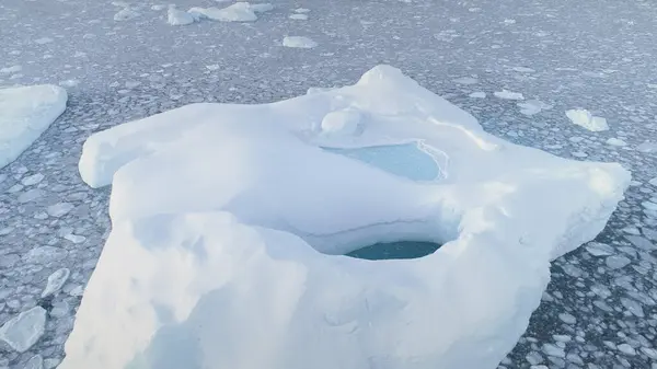 Melting Iceberg Pool Brash Ice Aerial Zooming Out. Massive Snow Ice with Hole Float in Antarctica Sea Water, Global Warming Concept. South Pole Glacier Landscape. Drone Top Footage Shot in 4K UHD
