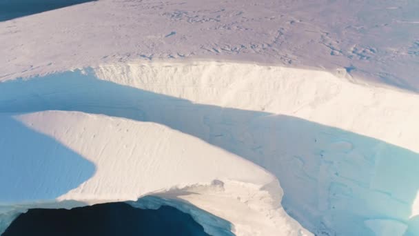 裂开的冰 巨大的破裂的北极冰川空中景观 在明亮的阳光下 冰山在南极洲深深破裂 全球变暖的环境生态问题 冬日阳光灿烂的极地气候变化 — 图库视频影像