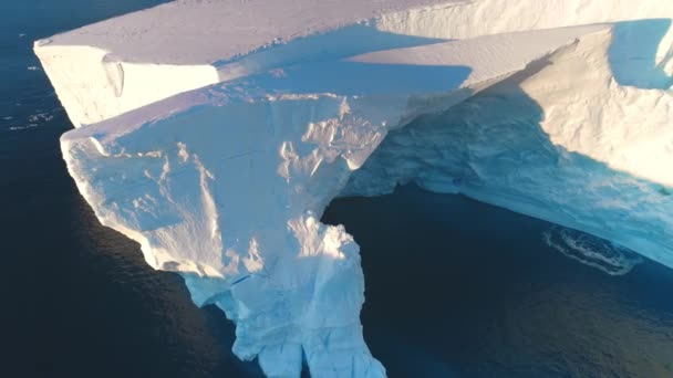 巨大的南极蓝色冰山洞穴在夕阳西下明亮的阳光下 巨大的冰川在极地自然环境中坠毁了 生态学 融化的冰 气候变化和全球变暖的概念 空中无人驾驶飞机全景 — 图库视频影像