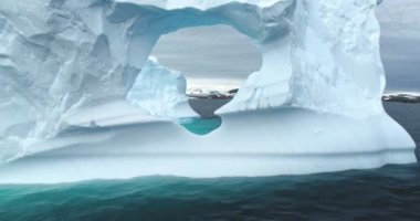 Erimiş delikte insansız hava aracı uçuşu kutup okyanusu kıyısında yüzen devasa bir buzdağı. Büyük beyaz buzullar soğuk su kutup ortamında sürükleniyor. Ekoloji, eriyen buz, iklim değişikliği ve küresel ısınma kavramı