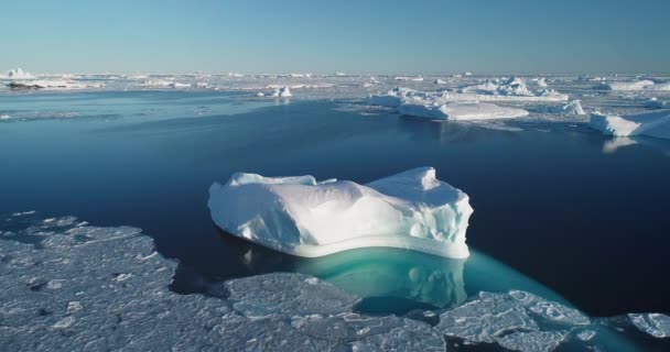 白色的大冰川漂移着原始的北极冰原景观 巨大的冰山漂浮在极地冰冷的海水中 阳光灿烂 电影生态学场景 融化的冰 气候变化 空中无人驾驶飞机镜头 — 图库视频影像