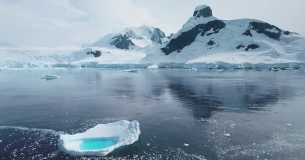 南極は青い水の氷山を溶かしています 南極の海洋環境 北極の氷河フロート極海の風景 雪は背景に山を覆いました シネマティックエコロジーシーン 空中ドローン飛行 — ストック動画