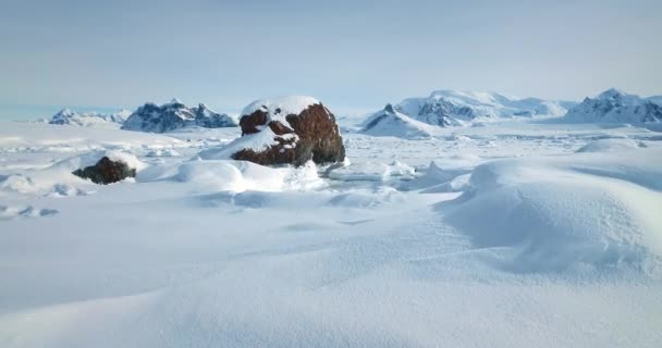 阳光明媚的冬季北极雪景 白茫茫的荒漠 冰雪覆盖的土地 背景上覆盖着高山 在冰冻的南极景观上进行着令人惊叹的旅行 低角度无人驾驶飞机射击 — 图库视频影像