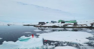 Bilim adamları Antarktika 'da eriyen buzulları araştırıyorlar. Turuncu dalgıç elbiseli iki adam eriyen buz kütlesi okyanus suyunun üzerinde duran örnekler alıyor, iklim değişikliği sorunu. Kutup istasyonu gezisi. Hava aracı uçuşu