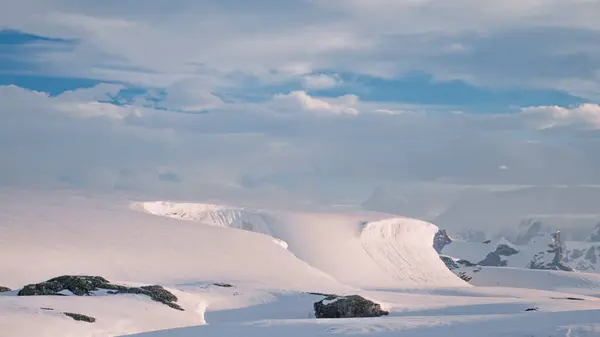 Clouds run over icebergs mountain ranges aerial. Wild scenery of snowy and icy mount peaks in Antarctica, South pole. Nobody nature landscape of world snow desert. Climate change concept