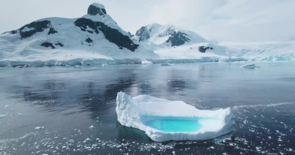 南極大陸の空中パノラマに浮かぶ氷山を溶かす 氷河の氷の形成は 極海を漂流する内部の青い湖と 雪は背景に山を覆いました 冬の風景 シネマティックエコロジーシーン — ストック動画