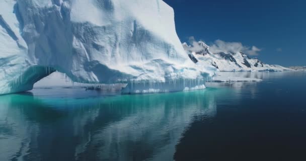 南極大陸の大きな氷河のアーチを溶かす 穏やかな水に映し出された氷山 エコロジー 氷の融解 気候変動 地球温暖化 クリスタルオーシャンクローズアップ上の低角度ドローン飛行 — ストック動画