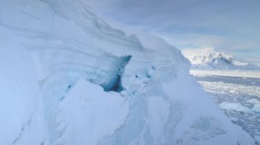 Antarktika Yarımadası 'ndaki beyaz buzuldaki mavi buz mağarası. Havadan yakın çekim. Antarktika panoramik dron uçuş görüntüsü. Kutup buzullarının arasında kar. Donmuş suyun etrafındaki buzdağında bir mağara. Donmuş toprak. Antarktika