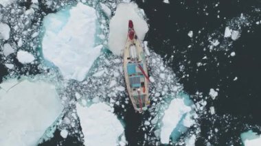 Yelkenli yatı Antarktika sahillerindeki buz dağının içinden geçiyor. Kırmızı Yat 'ın yakın plan görüntüsü Antarktika' daki eriyen buzu kırıyor. Havadan Yukarıdan Aşağıya Vuruldu. Okyanus Gemisi Keşfi Kutup Doğasını Keşfet