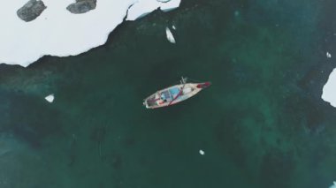 Antarktika Okyanusu 'nda Yat Yelkeni. Havadan Yukarıdan Aşağı Görünümü. Küresel Isınma Etkisi İçin Yelkenli Gemi Kar Kutbu Kristal Temiz Zümrüt Suyu Keşfediyor. Kuzey Kutbu kıyısında ve buzlu kıyılarda. Drone görünümü.