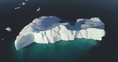 Antarktika 'da dev bir buzulda dinlenen iki fok. Soğuk okyanusta yüzen yalnız bir buzdağı. Vahşi kutup hayvanları, dokunulmamış kutup doğası. Küresel ısınma ve iklim değişikliği. Üst görüntü insansız hava aracı görüntüsü
