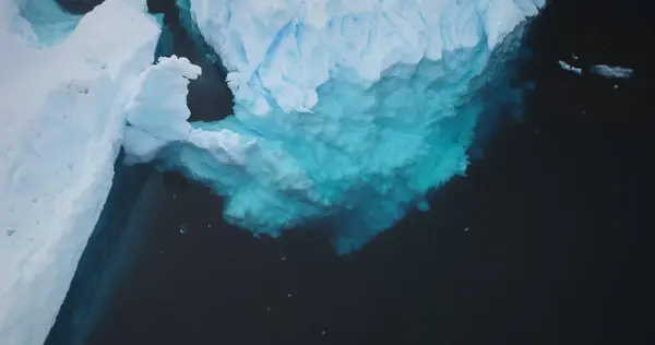 Antarctic iceberg underwater melting ice, global warming, ecology, climate change concept. Close up snow covered crashed glacier with cavity floating cold Polar ocean. Aerial panorama.