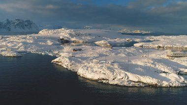 Antarktika kutup istasyonu Vernadsky Üssü üzerindeki insansız hava aracı görüntüsü. Okyanus kıyısı - açık su yüzeyi. Kar güney kutbu yerleşimlerini kapladı. Görkemli peyzaj uçuşu
