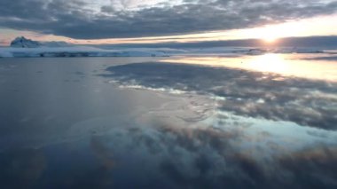 Arktik okyanus gün batımı, soğuk kutup buzlu sularına yansıyan gökyüzü. Gökyüzündeki renkli parlak bulutlar. Dokunulmamış vahşi doğanın güzelliği. Antarktika 'daki vahşi yaşamı araştırın. Kış seyahati manzarası. Hava aracı uçuşu