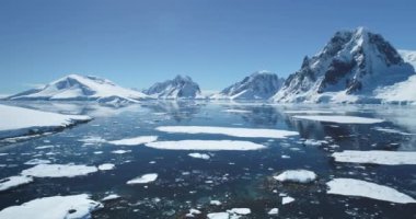 Güneşli bir günde Antarktika okyanus körfezi hava manzarası. Su yüzeyinde eriyen buz, mavi gökyüzü, arka planda karla kaplı dağlar. Antarktika gezisi keşfi. Güney Kutbu 'nun güzelliğini keşfedin