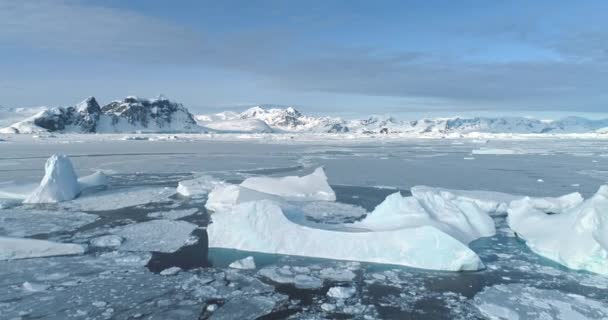 凍った北極の溶ける氷の浮遊の風景 冷たい極海に浮かぶ氷山 背景にある山々 南極大陸の氷河の海岸景観 エコロジー 気候変動 地球温暖化 — ストック動画