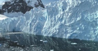 Devasa buzullar soğuk kutup okyanusu gibi yükseliyor. Kristal kutup suyuna yansıyan devasa bir buzdağı. Antarktika 'da kar kaplı buz duvarı. Ekoloji, eriyen buz, iklim değişikliği, küresel ısınma kavramı