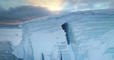 Günbatımı Antarktika manzarasında devasa bir buzul duvarı. Antarktika 'daki bir buzdağının nefes kesici manzarası. Kuzey Kutbu 'nda buzlar korunuyor. Kutup doğasında büyük bir buz kütlesi. Hava aracı panoraması