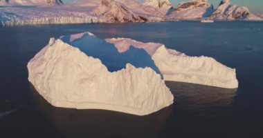 Dev donmuş buzullar gün batımında sürükleniyor kutup okyanusu. Antarktika 'da devasa buzdağları eritiyor, doğanın gücü. Ekoloji, eriyen buz, iklim değişikliği ve küresel ısınma kavramı. Hava aracı uçuşu