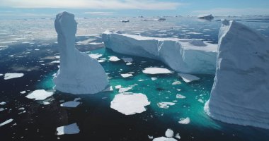 Eriyen buzdağı mavi su koyunda yükseliyor, Antarktika güneşli gün manzarası. Kutup okyanusunda yüzen buzuldan kopmuş buz. Ekoloji, eriyen buz, iklim değişikliği ve küresel ısınma. Hava aracı görüntüsü