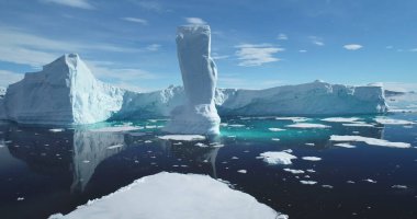 Antarktika 'nın devasa buzdağı eriyen buzul sularında sürüklenir, büyük buzuldan düşer. Güneşli mavi gökyüzü. Küresel iklim değişikliği ve eriyen buzdağları sorunu. Ekoloji, eriyen buz, küresel ısınma kavramı