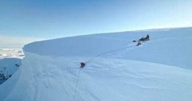 Bir grup insan Antarktika 'nın buzul hava görüntüsünü gevşetiyor. Karla kaplı yamaç, güneşli bir günde mavi gökyüzü. Güney Kutbu güzelliğini keşfedin. Antarktika seyahati, keşif, keşif. Kürekle kar kazan adam