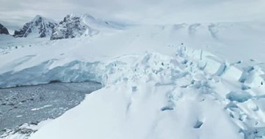 Antarktika 'da dev buzul kütleli kutup okyanusu. Kar, soğuk karanlık suyun üzerinde yükselen mavi buzdağını örttü. Antarktika kış manzarası. Hava aracı sinematik ekoloji sahnesi çekti