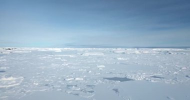 Donmuş kar, açık mavi gökyüzünün altında kutup okyanusu yüzeyini kapladı. Antarktika 'da beyaz battaniye çöl arazisi, kış manzarası. Güney Kutbu 'nu keşfet. Antarktika seyahati ve keşfi. Düşük açılı İHA uçuşu