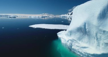 Soğuk kutup suyunun üzerinde yükselen büyük buzdağını kapatın. Panoramik çekim arka planda dağları kaplayan kar, güneşli bir günde parlak mavi gökyüzü. Keşfetmek, Antarktika 'ya seyahat etmek. İklim değişikliği, küresel ısınma