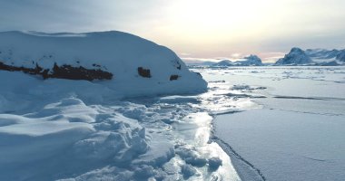 Kuzey Kutbu 'ndaki kış günbatımı manzarası karla kaplıydı. Arka planda donmuş kutup kayaları okyanus sıradağları var. Güney Kutbu 'nun güzelliğini keşfedin. Antarktika seyahati ve keşfi. Düşük açı Panorama 'yı kapat