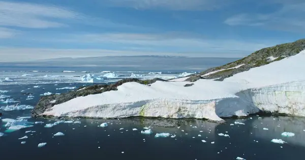 stock image Seagulls flying over pristine Antarctic landscape, sunny day. Mountain rock glacier, icebergs ice floating frozen polar ocean. Blue sky in background. Antarctica travel, explore wildlife. Aerial shot