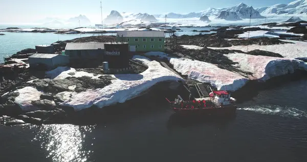 24.02.2020 Antarktika Yarımadası. Bilim adamları kutup kaşifleri Antarktika 'daki Vernadsky kutup istasyonunda keşif ekibini değiştiriyor. Kayalık kıyılarda yelken açan insanlarla dolu kırmızı bir tekne. Güney Kutbu 'nu keşfet. Hava görünümü