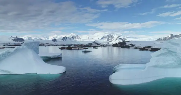 stock image Antarctica majestic seascape aerial view. Drone fly over melting huge glacier, icebergs, rocky coastline with snow covered mountains in background. Polar ocean under blue sky. Antarctic travel explore