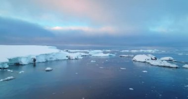 Antarktika okyanus kıyısında gün batımı kış manzarası. Soğuk kutup buzu üzerinde uçan hava uçuşu. Ekoloji, eriyen buz, iklim değişikliği, küresel ısınma. Vahşi doğa geçmişi, Güney Kutbu seyahati.