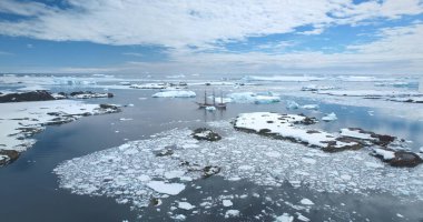 Wooden old style yacht anchored Antarctica coastline. Travel expedition boat tour to South Pole. Explore arctic wild nature. Polar ocean, icebergs, blue sky. Winter holiday vacation. Aerial shot clipart