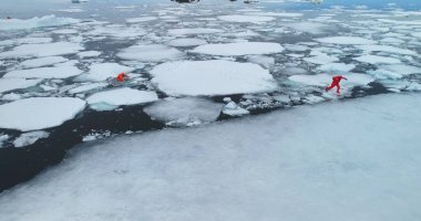 Antarktika 'daki insanlar donmuş buz kütleleri. Turuncu dalış elbiseli iki adam eriyen buzu, kutup yüzeyini, soğuk kutup sularına düşüyorlar. Buzdağlarını, iklim değişikliklerini, küresel ısınmayı araştırın. Havadan