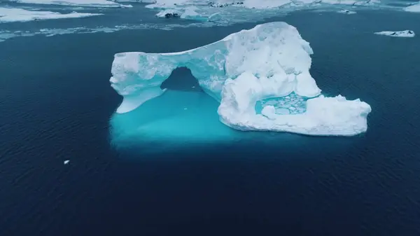 stock image Blue antarctic iceberg arch melting underwater. Huge cracked glacier floating cold blue polar water. Natural beauty of towering glacier Antarctica. Cinematic ecology scene. Aerial drone shot panorama