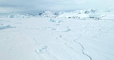 Towering mountains desert snow covered Antarctic landscape. Aerial drone fly over frozen ocean coast, ice floe crack. Beautiful South Pole winter wild nature footage. Antarctica travel and exploration