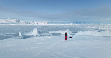 Antarktika 'daki insan, buzul üzerinde duran insansız hava aracını kullanıyor. Saf kış kutup manzarasının hava manzarası. Tepe karla kaplı, donmuş okyanus, buzdağları, buz kütleleri. El değmemiş Antarktika 'nın üzerinden uç.