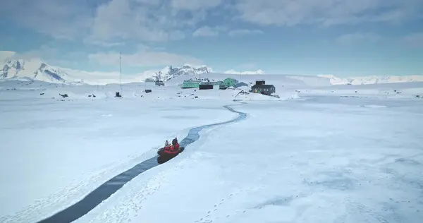 stock image Scientist from polar station base riding zodiac boat in melted steam. Frozen ocean ice, mountains and science buildings in background. South Pole tourism, travel, expedition. Aerial drone panorama