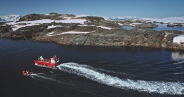 Antarktika 'ya bilimsel araştırma gezisi. Vernadsky Ukraynalı kutup kaşifleri değişim geçiriyor. Seyahat, Güney Kutbu 'nda turizm. Vahşi doğa okyanusunda yelken açan kırmızı bottaki insanlar. Hava aracı görüntüsü