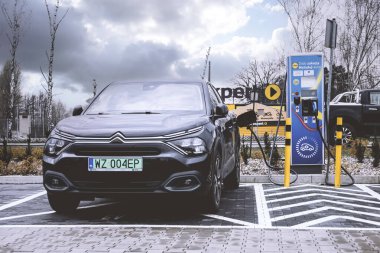 Şimdi Tomysl, Polonya - 21 Mart 2024. Otoparkta şarj olan elektrikli bir araba..